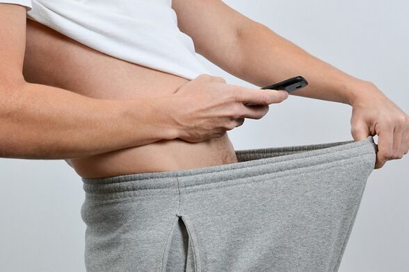 gizon batek praketan behera begiratzen dio zakil handitu bati